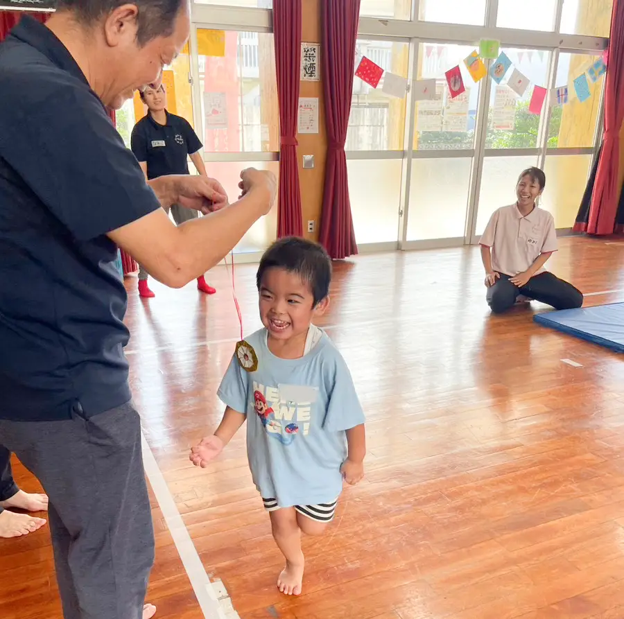南風原町のミニミニ運動会で、メダルをかけてもらって笑顔になる男の子